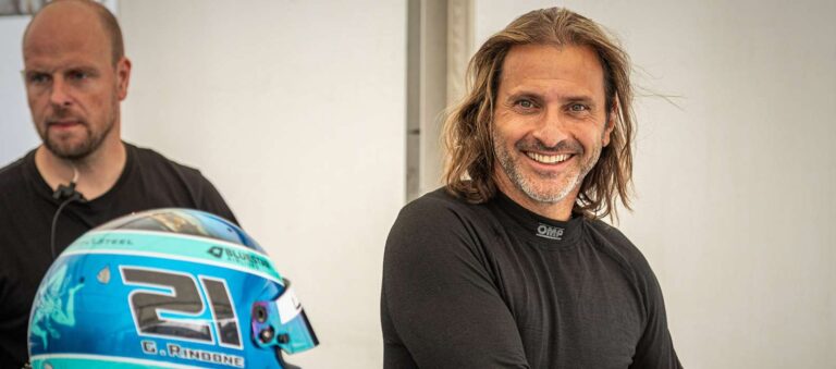 Gabriel Rindone posant fièrement devant une Lamborghini de course, illustrant son succès dans le sport automobile