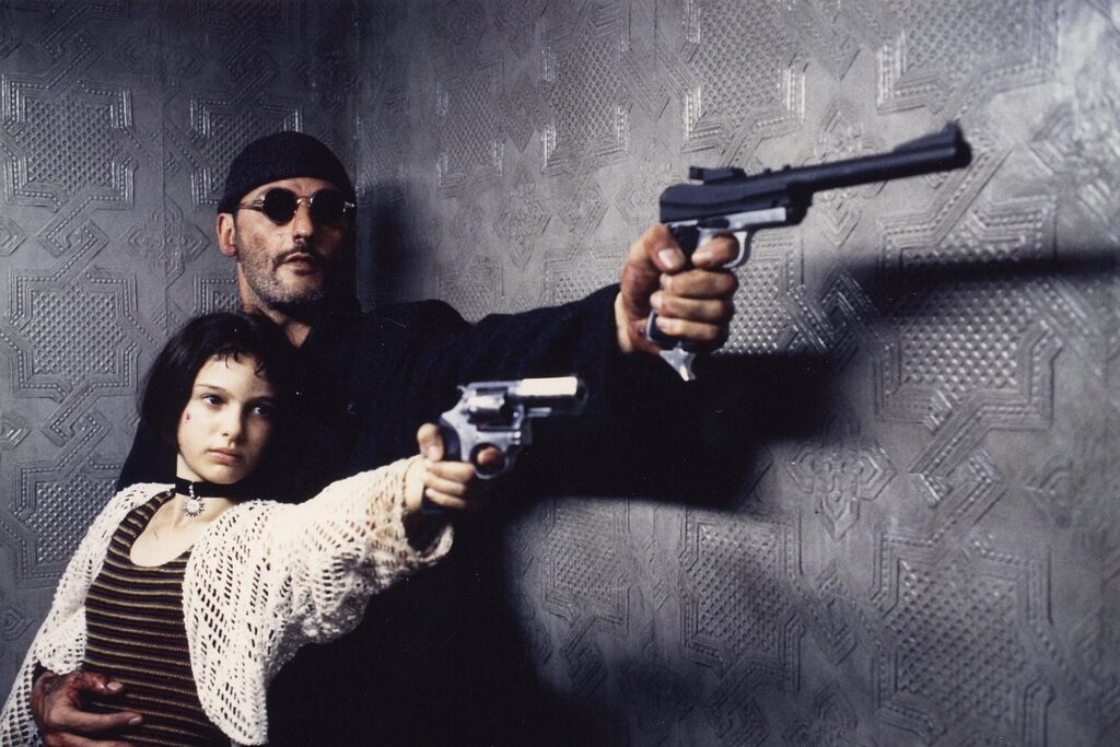 Jean Reno assis en costume, portrait d'une icône du cinéma français avec une fortune impressionnante