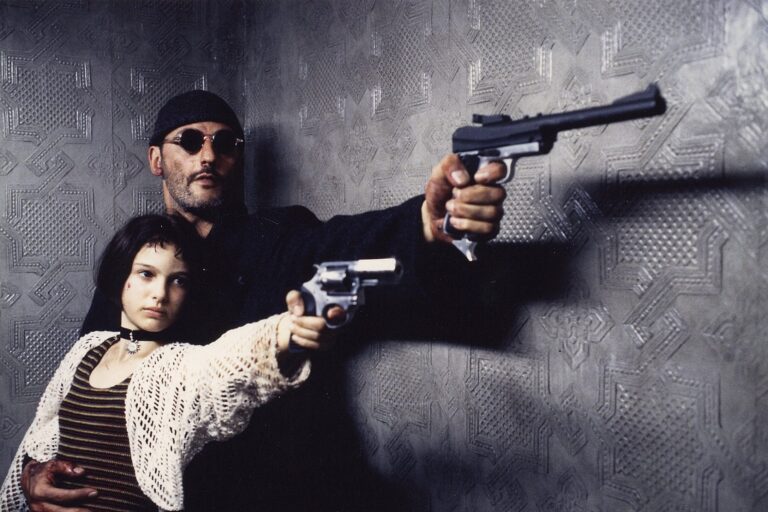 Jean Reno assis en costume, portrait d'une icône du cinéma français avec une fortune impressionnante