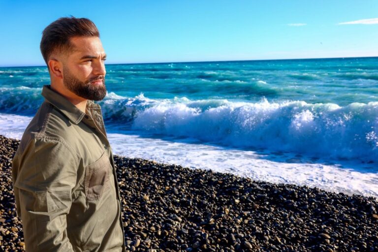 Kendji Girac souriant en arrière-plan flou, symbole de son succès musical et financier